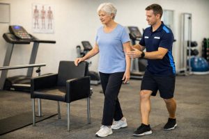 Accredited exercise physiologist supervising tandem stance balance training for falls prevention in a clinic setting