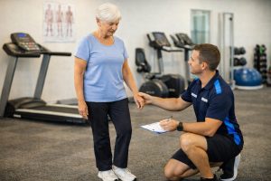 Exercise physiologist performing a balance and falls risk assessment with an older adult in a clinic setting